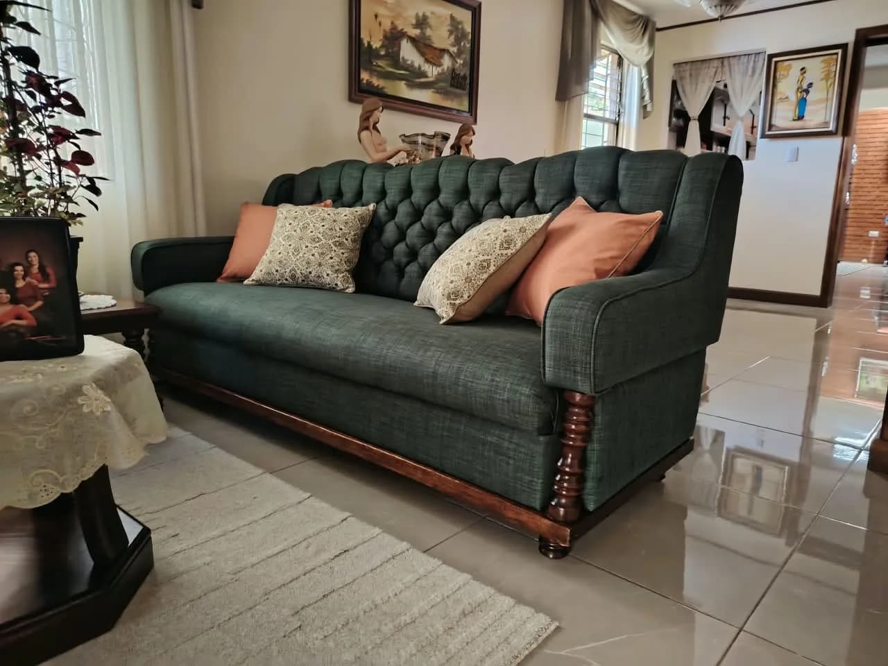 Sofá de tres puestos tapizado en lino verde con respaldo capitoné, instalado en una sala